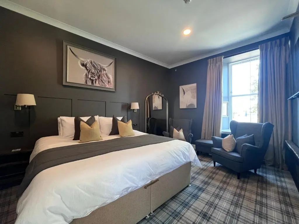 a hotel room with a large bed and a chair at Fraser House in Inverness
