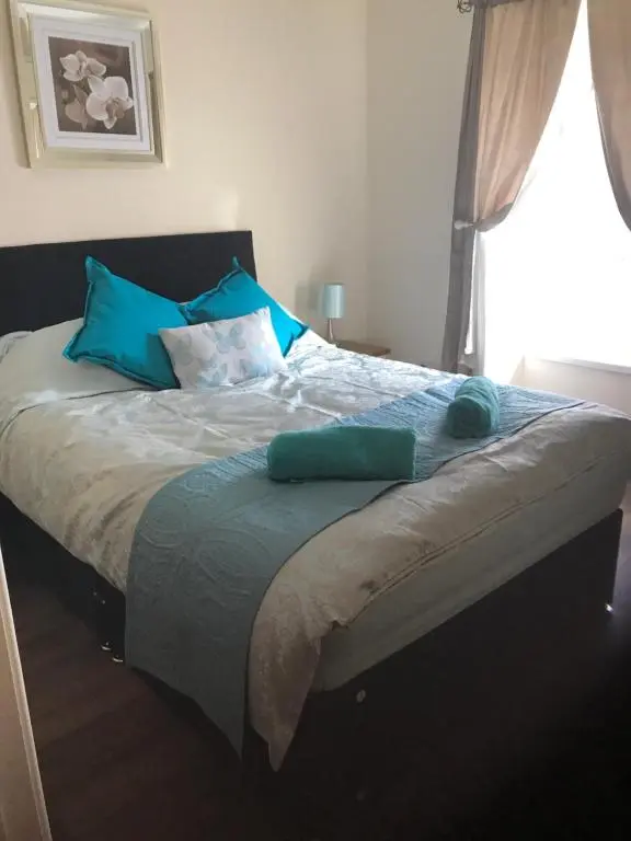 a bedroom with a large bed with blue pillows at River Ness Apartments in Inverness