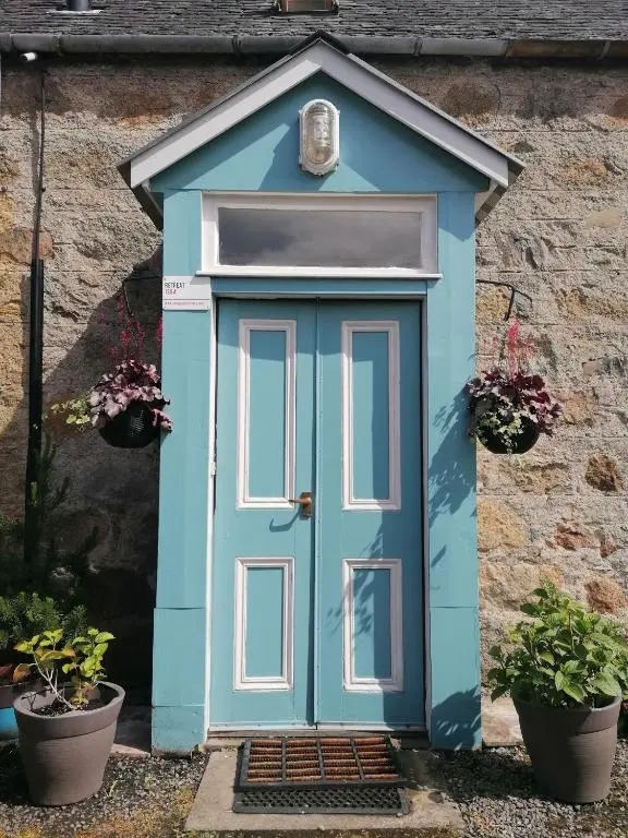 a blue door on a house with two potted plants at Aberlour Cottages - Bolthole & Retreat in Aberlour