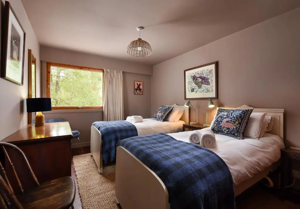 a bedroom with two beds and a desk and a chair at Cairngorm Lodge Rothiemurchus in Aviemore