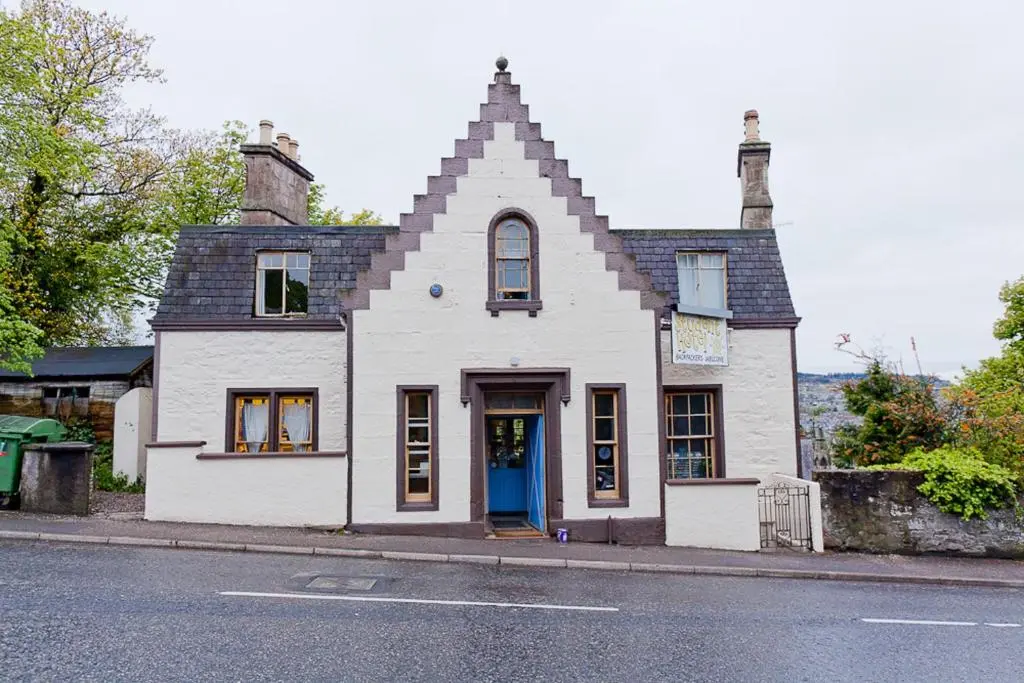 a white house with a blue door on a street at Inverness Student Hotel in Inverness