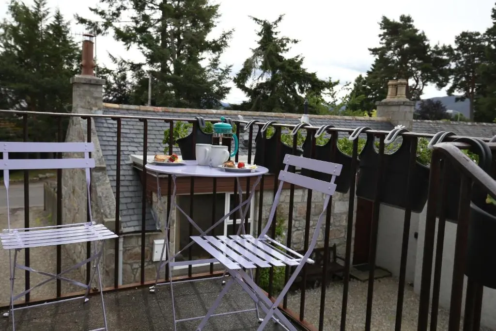 a table and two chairs on a balcony at High Terrace Apartment in Boat of Garten