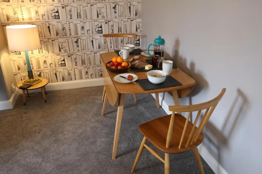 a table with a bowl of fruit on it with two chairs at High Terrace Apartment in Boat of Garten