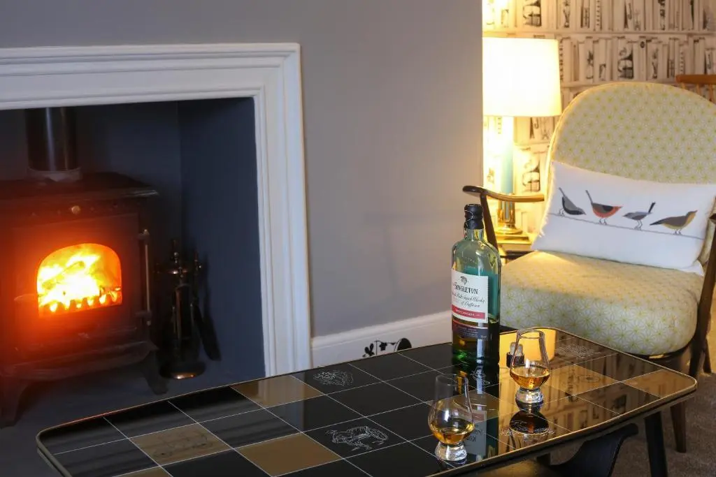 a bottle of wine sitting on a table next to a fireplace at High Terrace Apartment in Boat of Garten