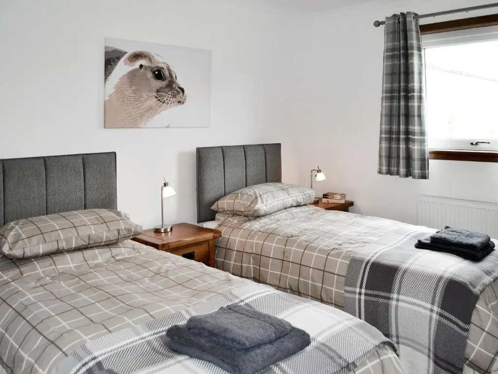 a bedroom with two beds and a cat picture on the wall at Auldfield in Lhanbryd