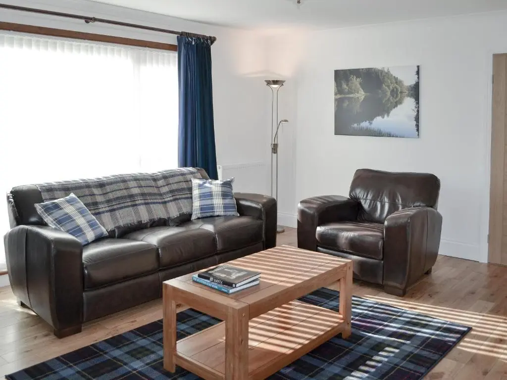 a living room with a leather couch and a coffee table at Auldfield in Lhanbryd
