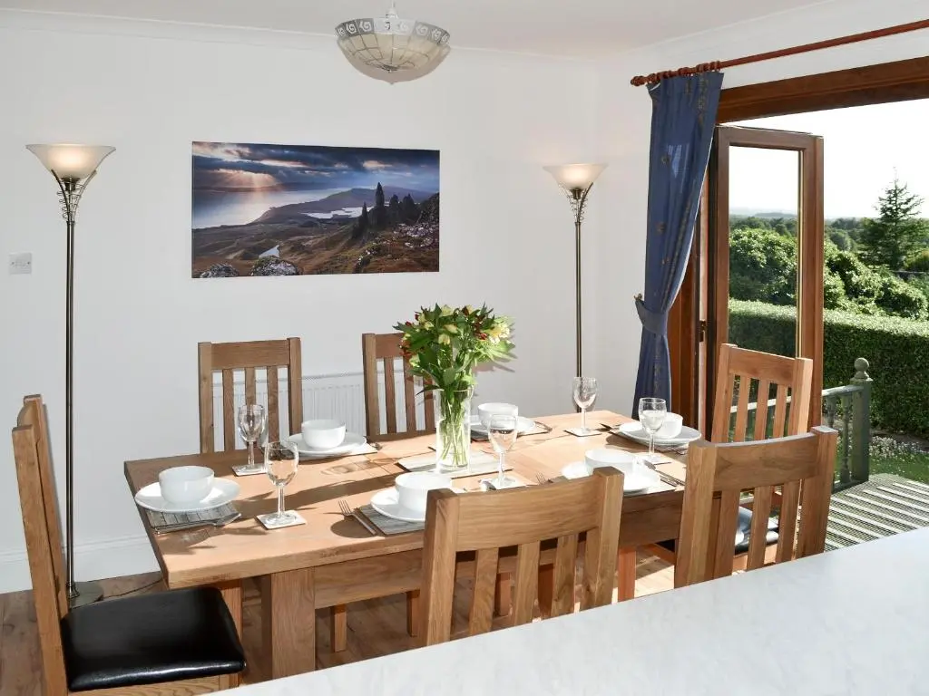 a dining room with a wooden table and chairs at Auldfield in Lhanbryd