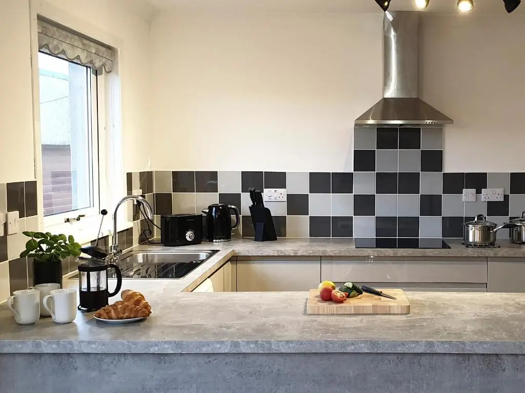 a kitchen with black and white tiles on the wall at Auldfield in Lhanbryd