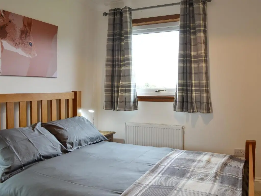 a bedroom with a bed and a window with curtains at Auldfield in Lhanbryd