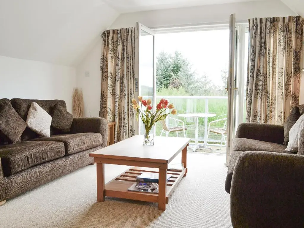 a living room with a vase of flowers on a coffee table at 32 Queens Court in Inchmarlo