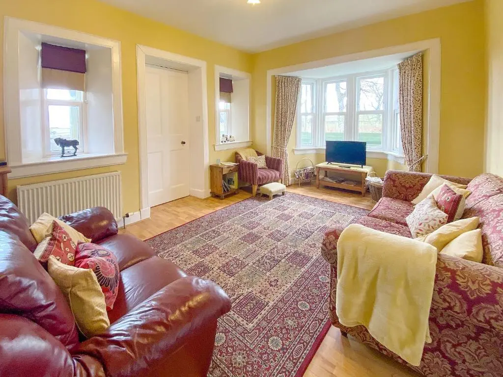 a living room with a leather couch and a rug at The Gate Lodge in Latheron