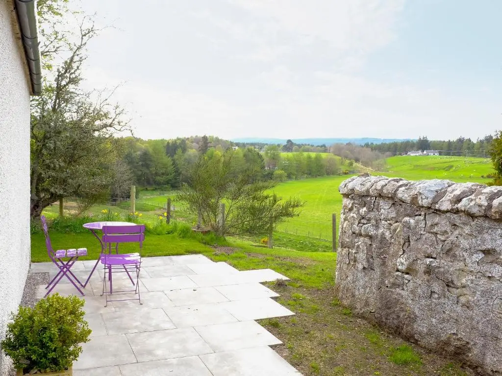 a patio with a table and chairs and a stone wall at The Barn in Ankerville