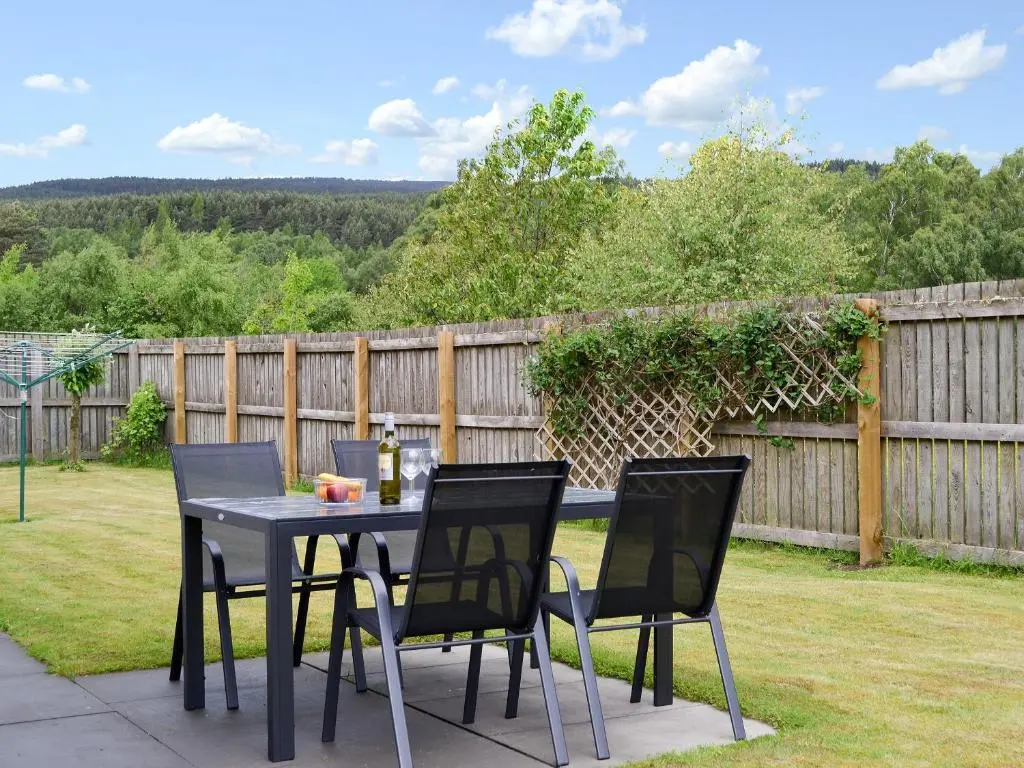 a table with four chairs and a bottle of wine at Stags Neuk in Aviemore