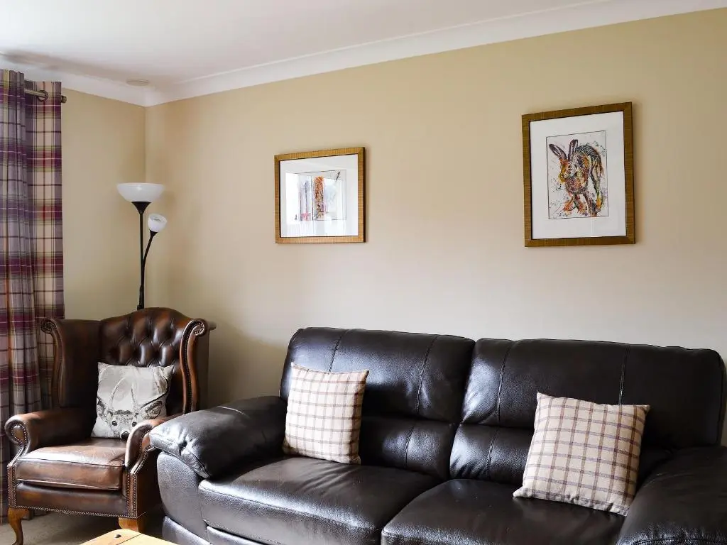 a living room with a leather couch and a chair at Stags Neuk in Aviemore