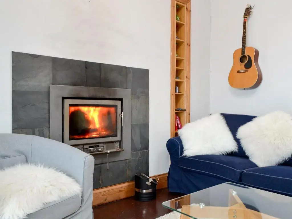 a living room with a blue couch and a fireplace at Sea Yonder in Buckie