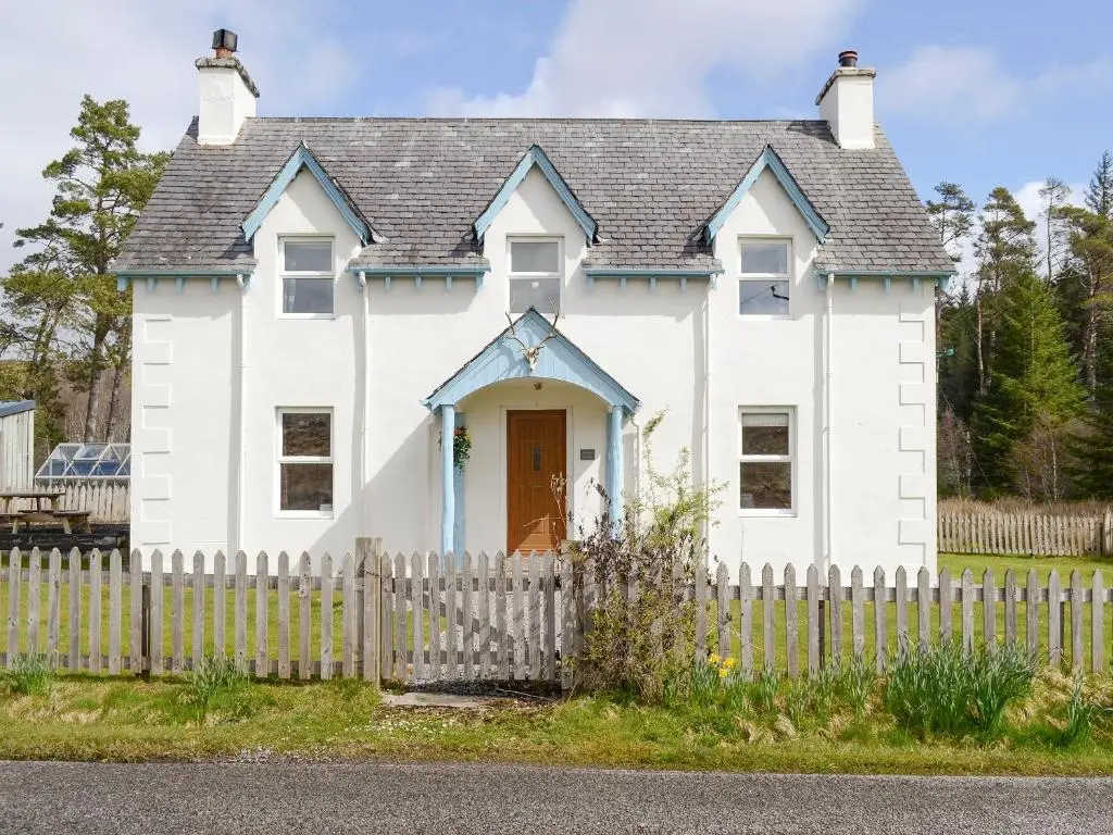 a white house with a wooden fence at Keeper's House in Glenrossal