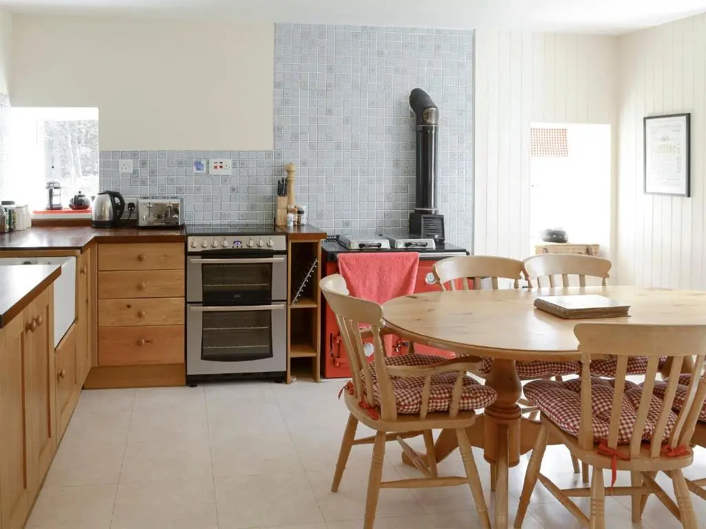 a kitchen with a wooden table and a table and chairs at Keeper's House in Glenrossal