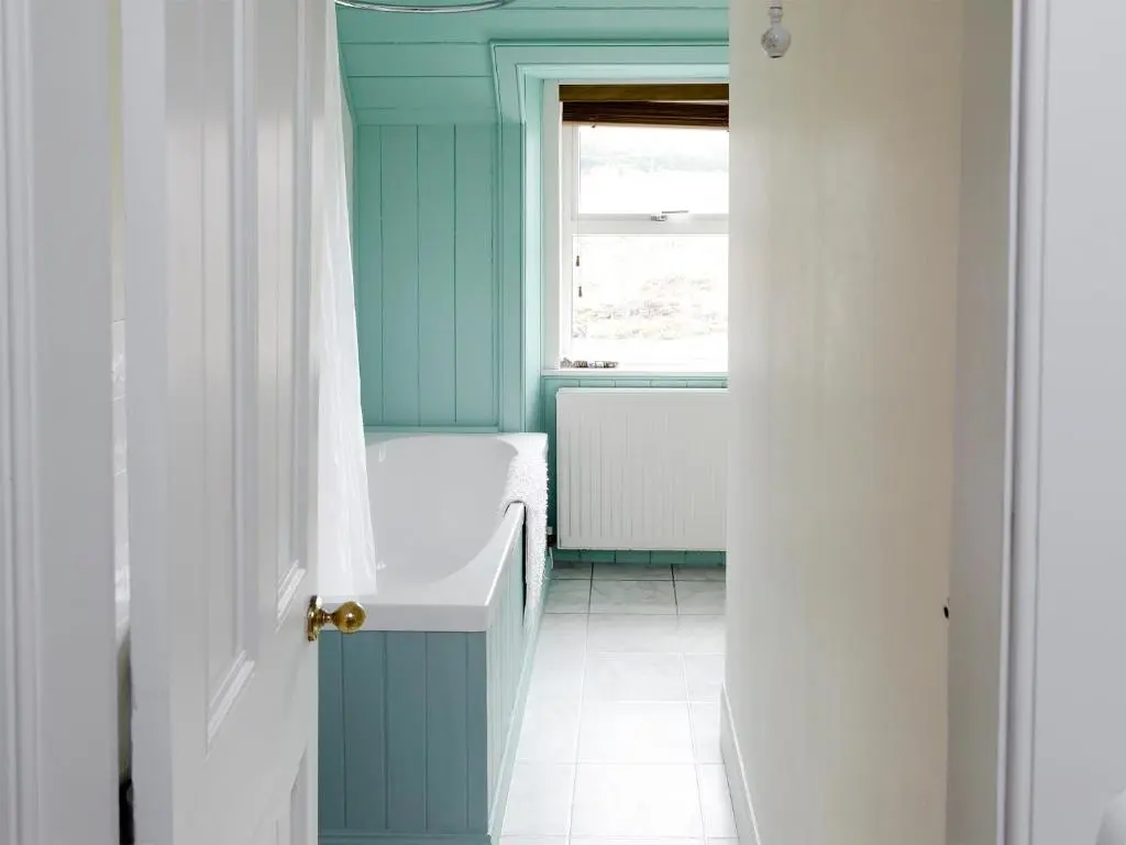 a bathroom with blue walls and a window and a tub at Keeper's House in Glenrossal