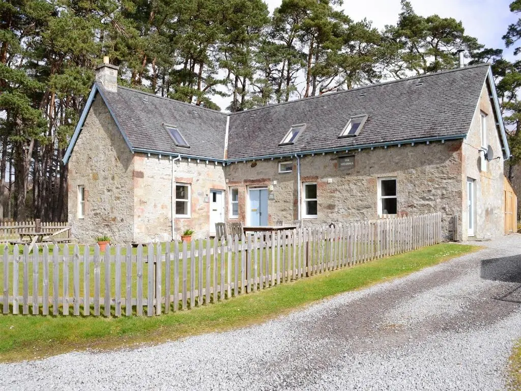 an old stone house with a wooden fence at Rowan Cottage in Glenrossal