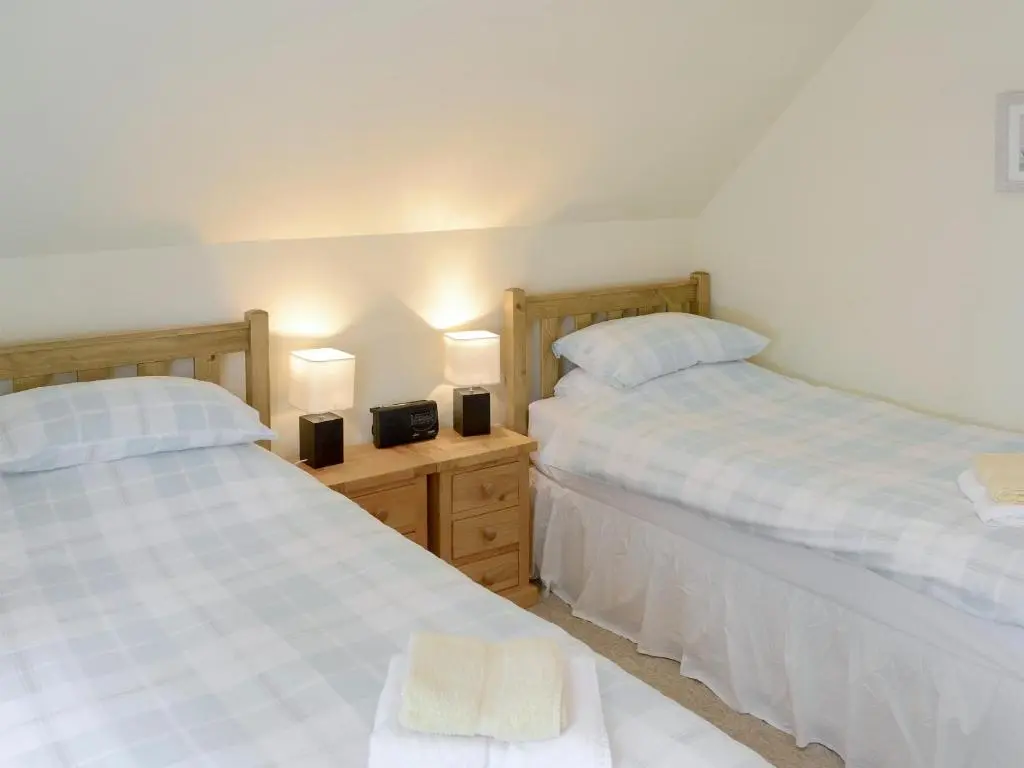two beds sitting next to each other in a bedroom at Rowan Cottage in Glenrossal