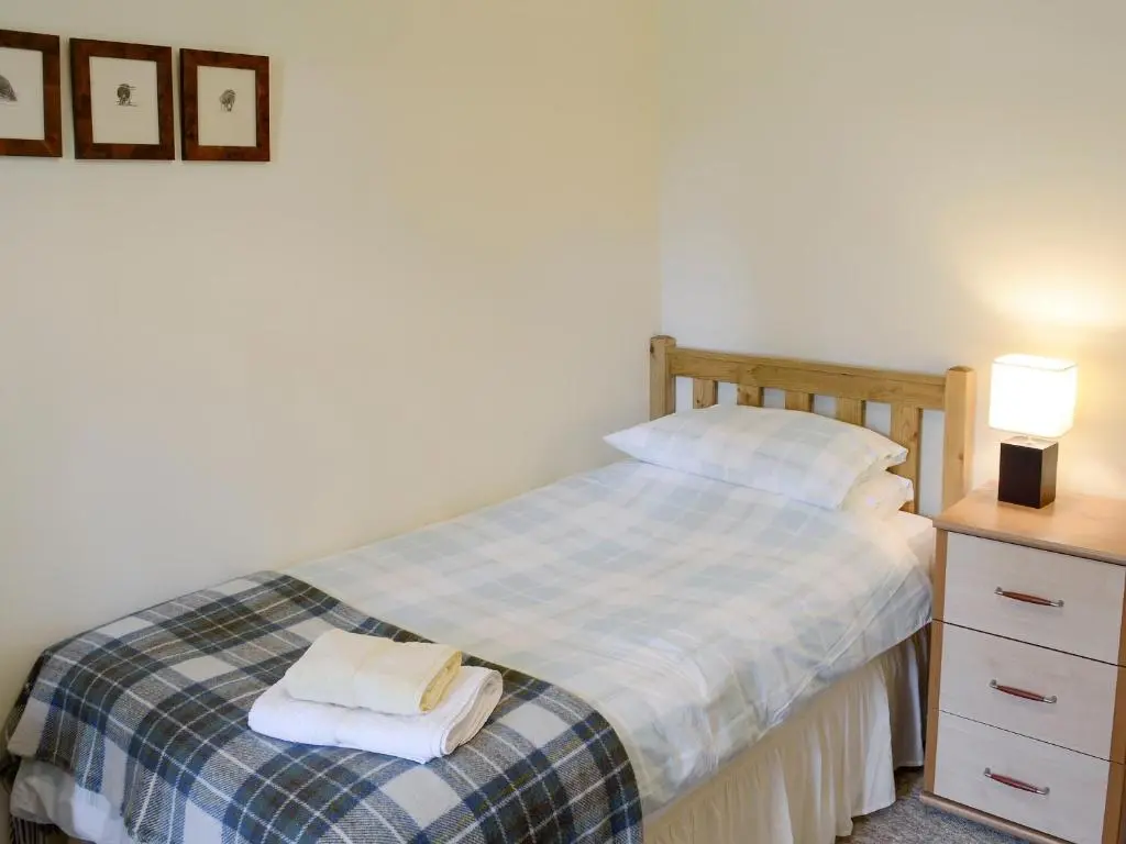 a bedroom with a bed with two towels on it at Rowan Cottage in Glenrossal