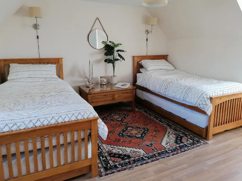 a bedroom with two beds and a table with a mirror at Rosslyn Cottage in Portmahomack