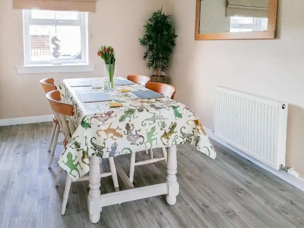 a dining room table with a table cloth on it at Rosslyn Cottage in Portmahomack