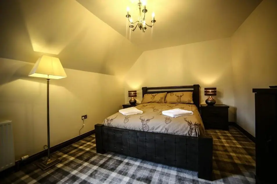 a bedroom with a bed and a lamp in it at Whitehouse B&B in Fort Augustus