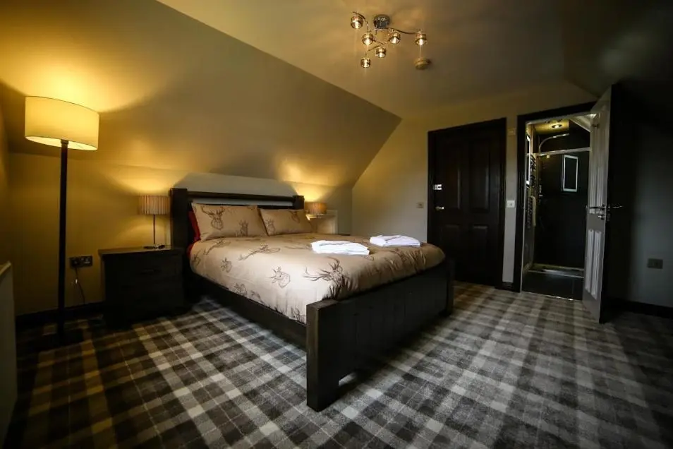 a bedroom with a bed and a lamp in a room at Whitehouse B&B in Fort Augustus