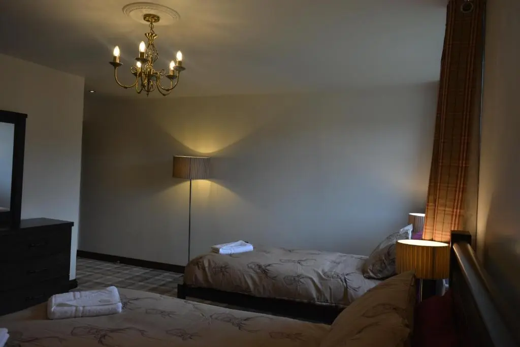a hotel room with two beds and a chandelier at Whitehouse B&B in Fort Augustus