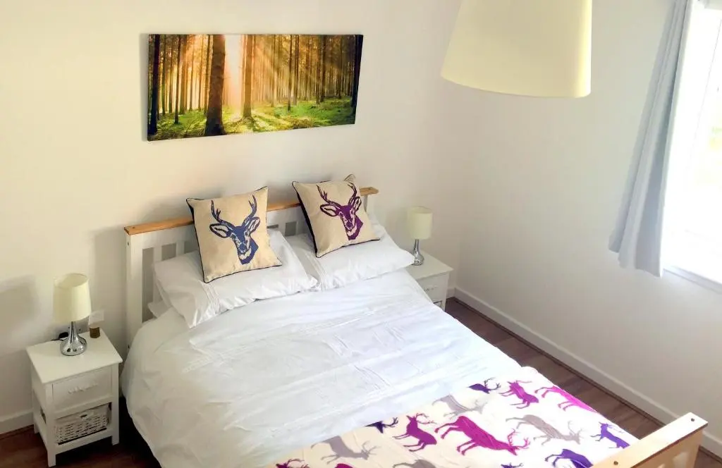 a bedroom with a bed with white sheets and pillows at Ventoux in Aviemore
