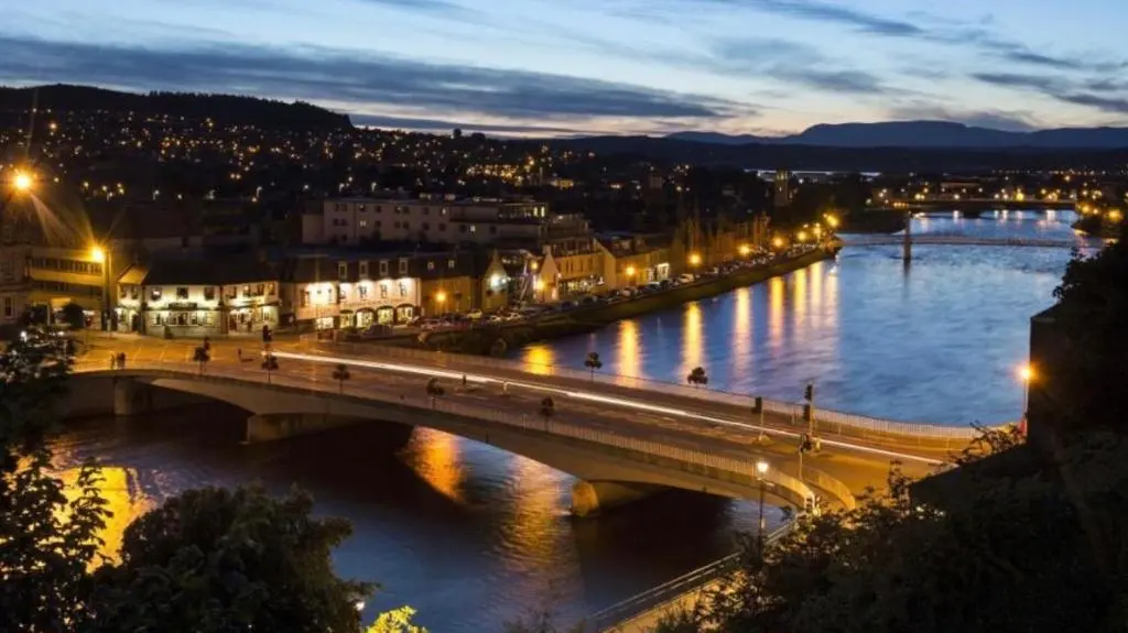 a bridge over a river in a city at night at Apartment 101 Kingsmills Road in Inverness