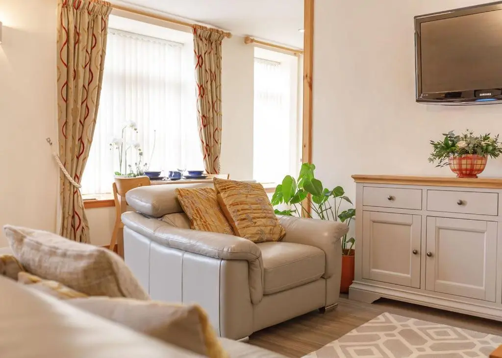 a living room with a couch and a television at The Old Dairy in Lairg