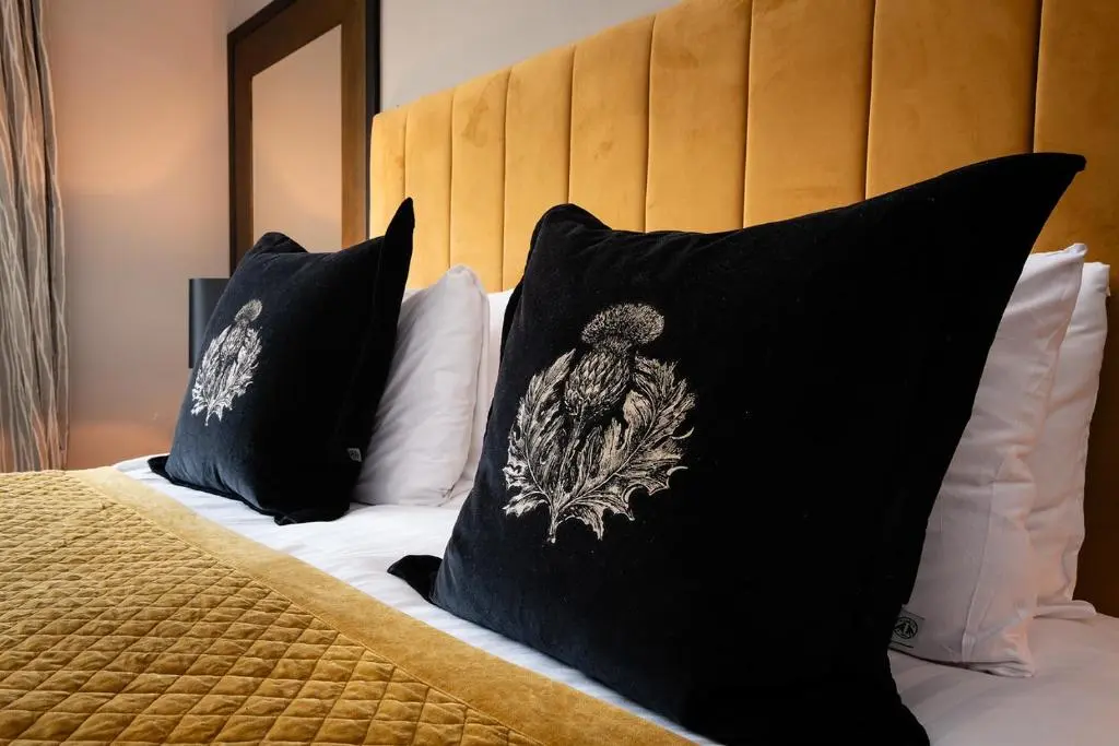 a bed with black and white pillows on it at The Old Manse of Blair, Boutique Hotel & Michelin Restaurant in Blair Atholl