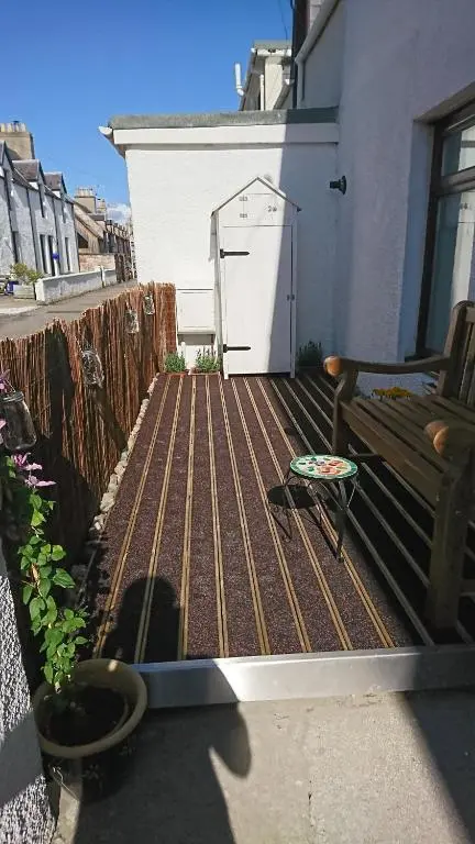 a wooden deck with a bench and a garage at Seaforth Cottage -Dog friendly, Historical Fishertown, central location in Nairn