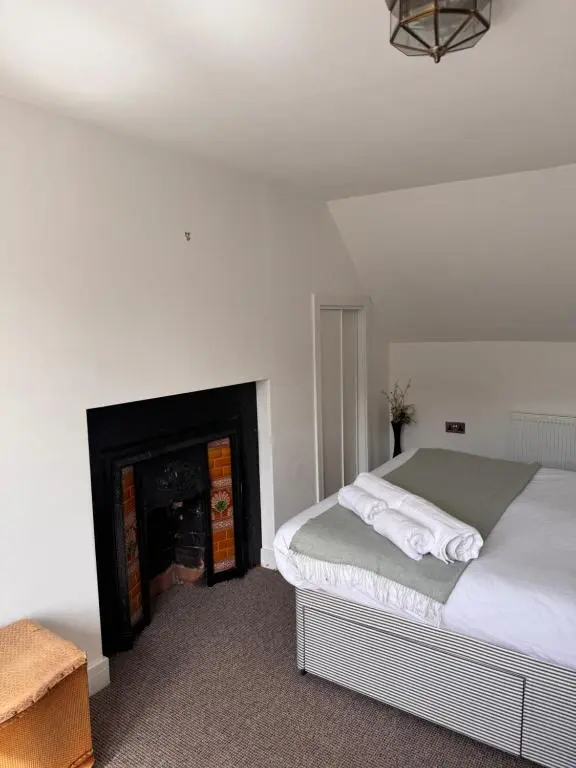 a white bedroom with a bed and a fireplace at Seaforth Cottage -Dog friendly, Historical Fishertown, central location in Nairn