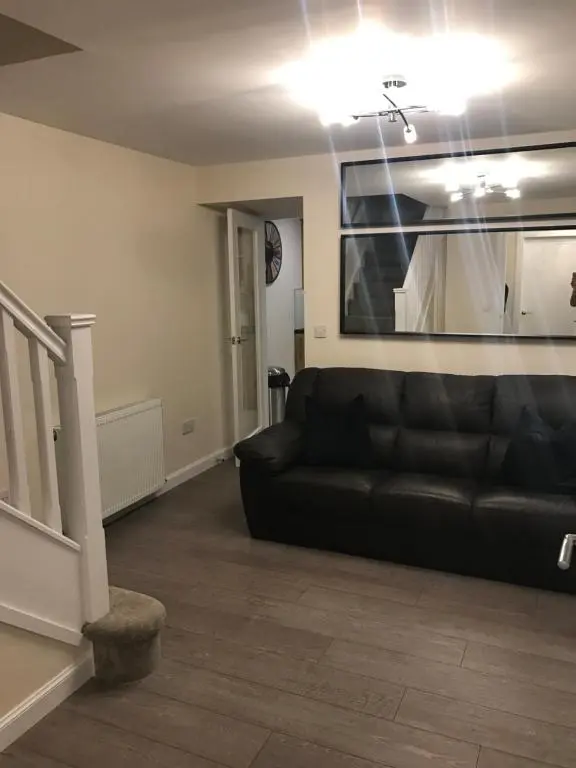 a living room with a black couch and a staircase at View Cottage in Inverness