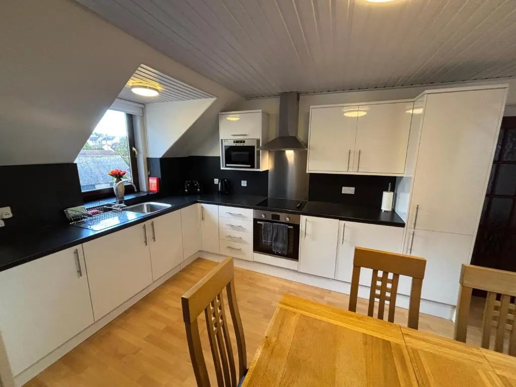 a kitchen with white cabinets and a table with chairs at The Coffee Pot accommodation in Dufftown