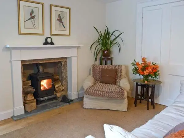 a living room with a fireplace and a chair at Easter Urray Farmhouse in Muir of Ord
