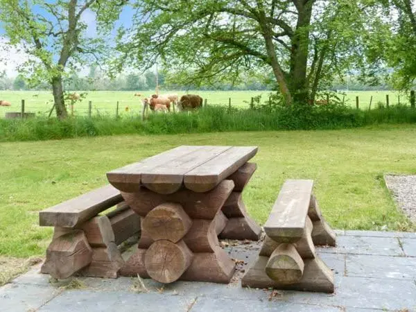 a wooden picnic table and benches in a field at Easter Urray Farmhouse in Muir of Ord