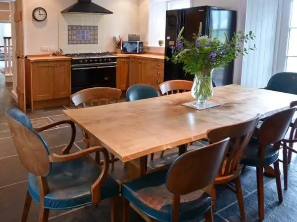 a wooden table with chairs and a vase of flowers on it at Easter Urray Farmhouse in Muir of Ord