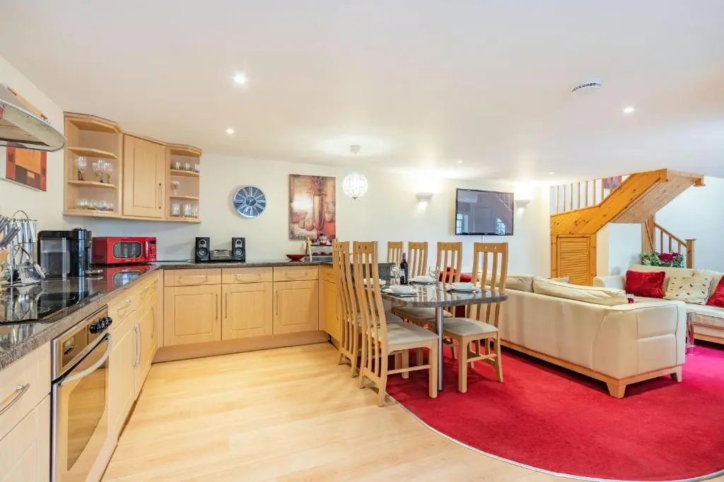 a kitchen and living room with a table and a couch at Dunstaffnage Cottage in Grantown on Spey
