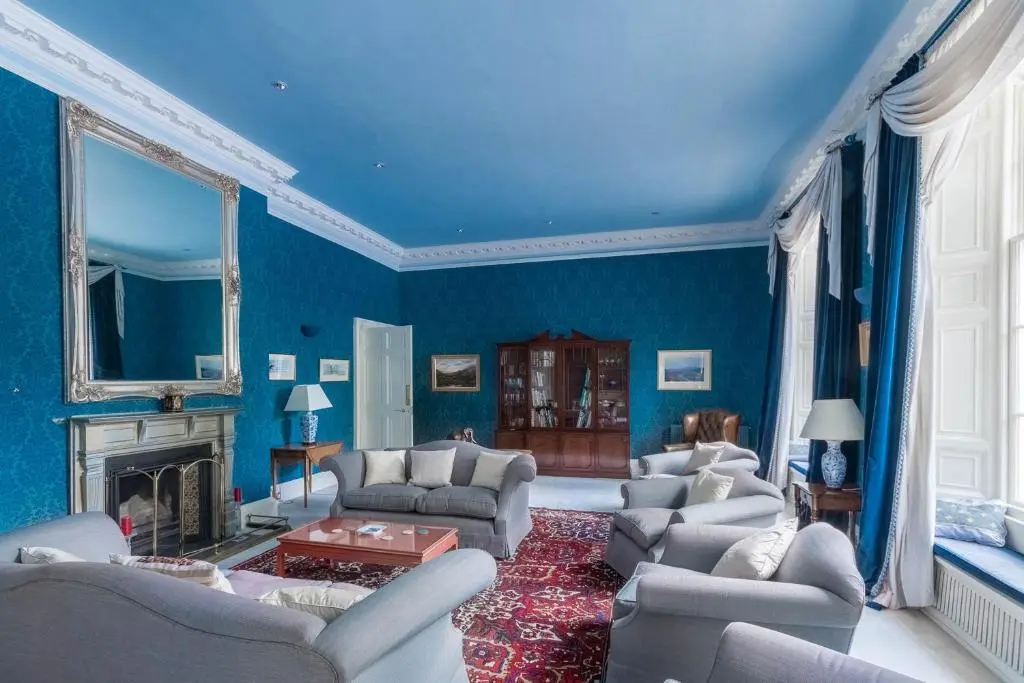 a blue living room with chairs and a fireplace at Blervie House in Forres