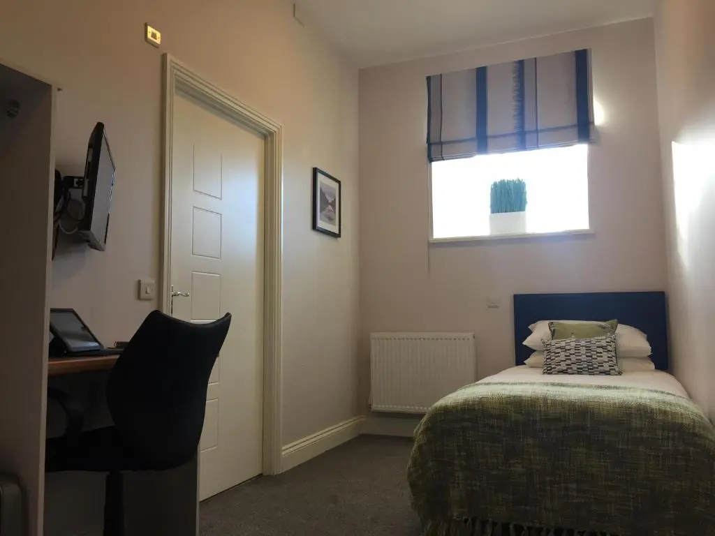 a bedroom with a bed and a desk and a window at The Sidings Inverurie in Inverurie
