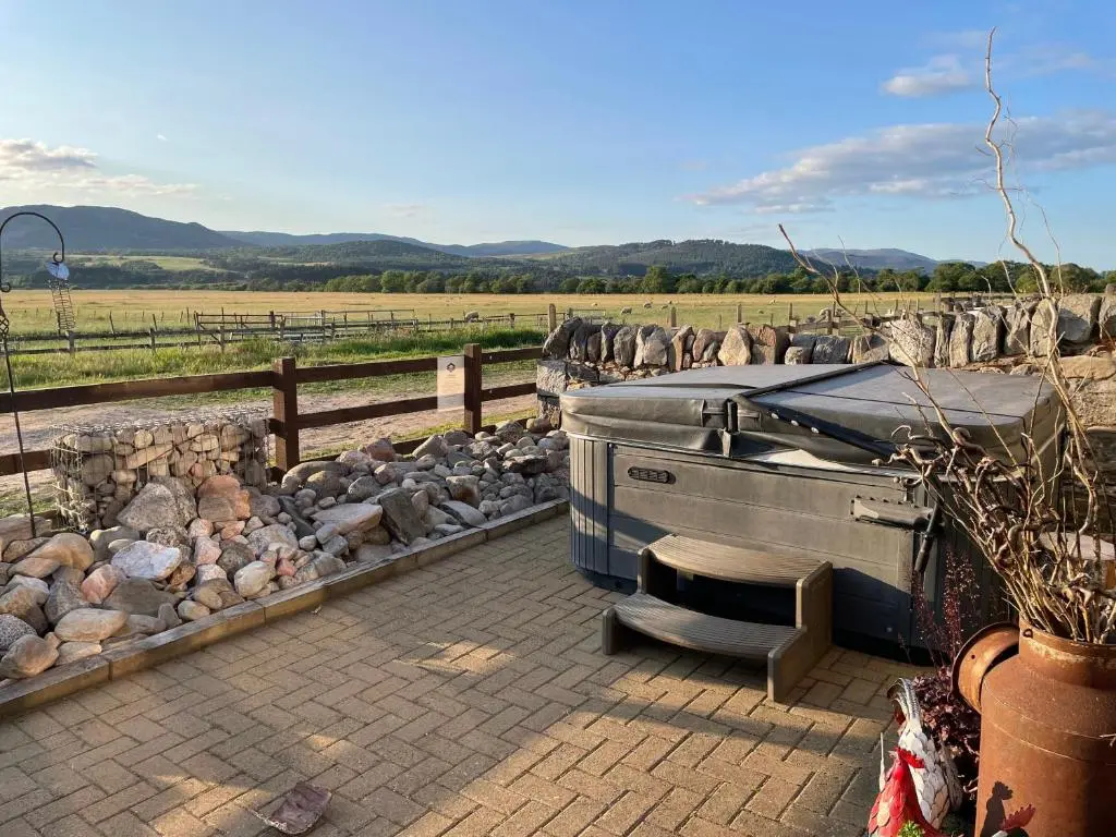 a patio with a grill and a pile of rocks at Osprey Lodge in Kingussie