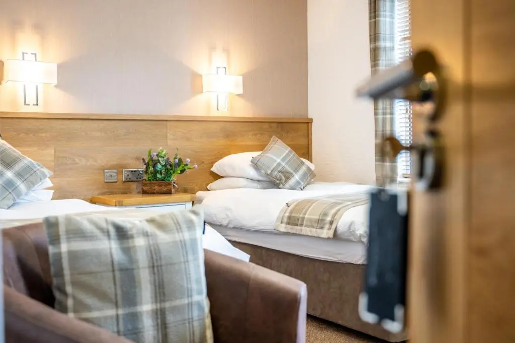 a hotel room with two beds and a chair at Riverside in Ullapool