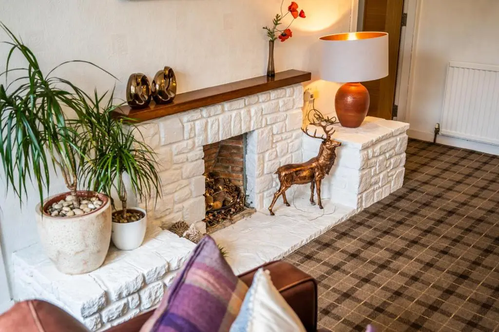 a living room with a fireplace with a statue of a deer at Riverside in Ullapool