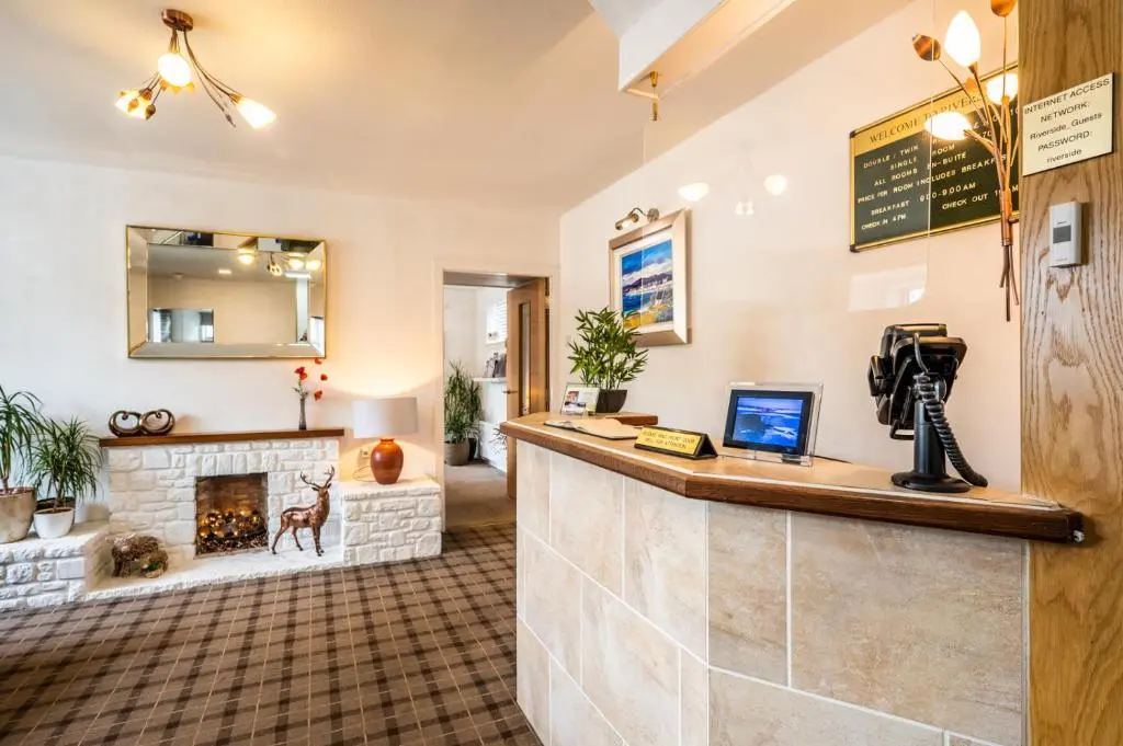 a hotel lobby with a reception counter and a fireplace at Riverside in Ullapool