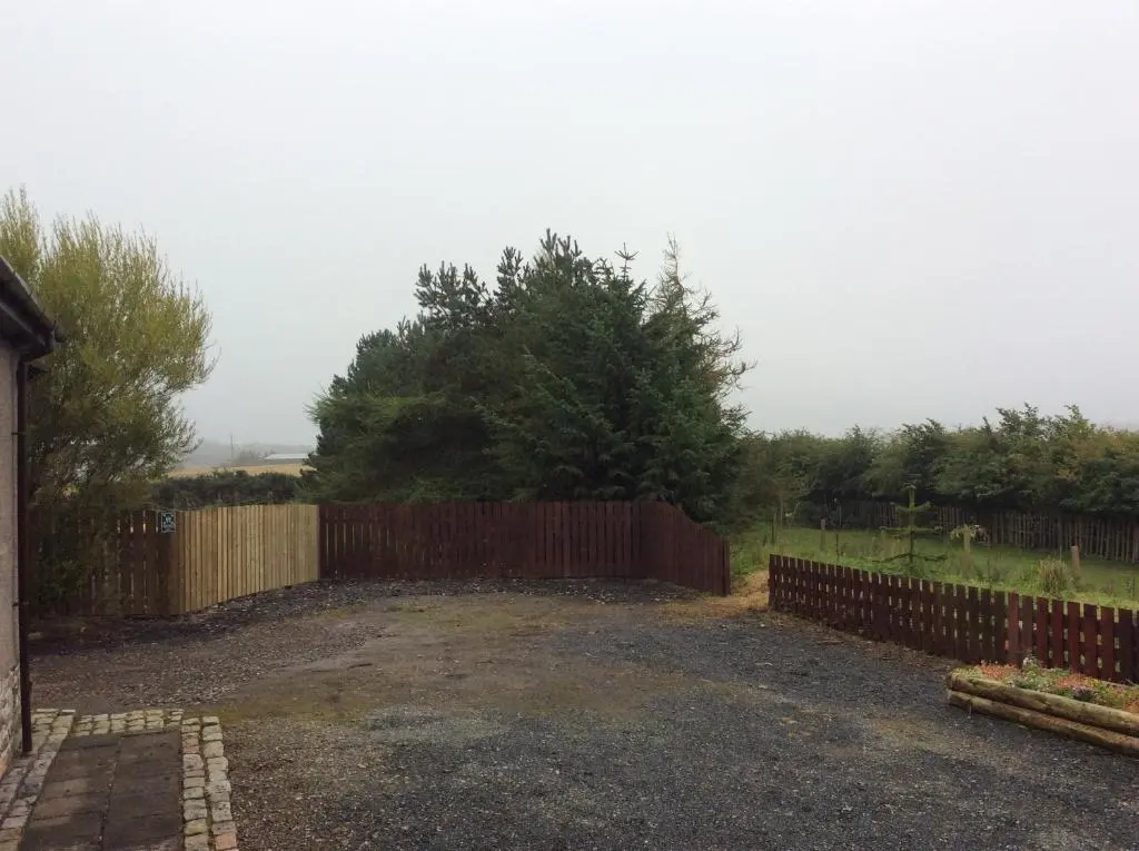 a fence in front of a yard with a tree at Rudan Guest House AB53 6UQ in New Deer