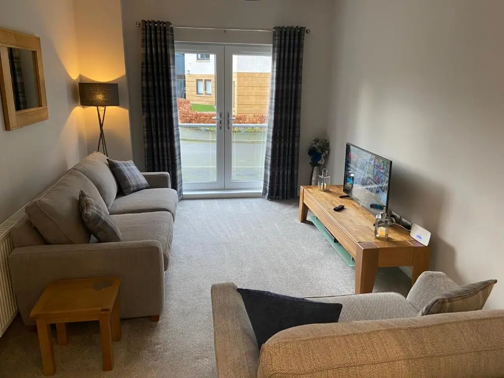 a living room with two couches and a table at 23 Hedgefield House in Inverness